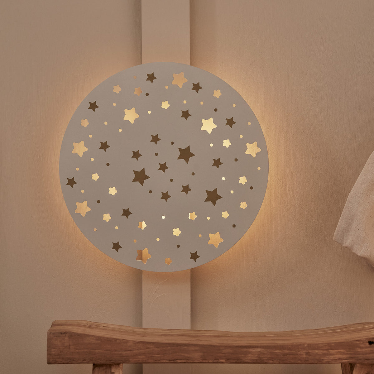 Runde Sternenhimmel Wandleuchte mit warmweißem Licht an Wand über Holzbänkchen