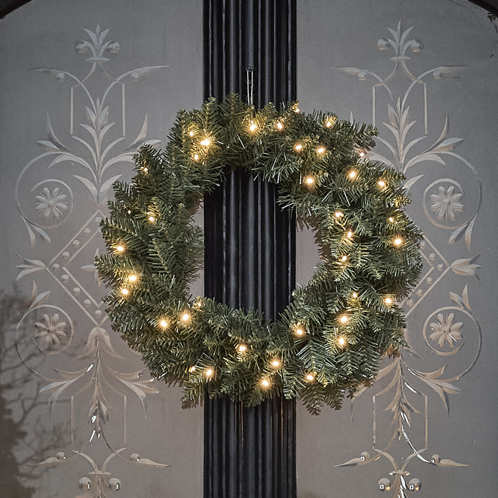 LED Weihnachtskranz mit Tannenzweigen und warmweißen Lichtern an schwarzer Tür
