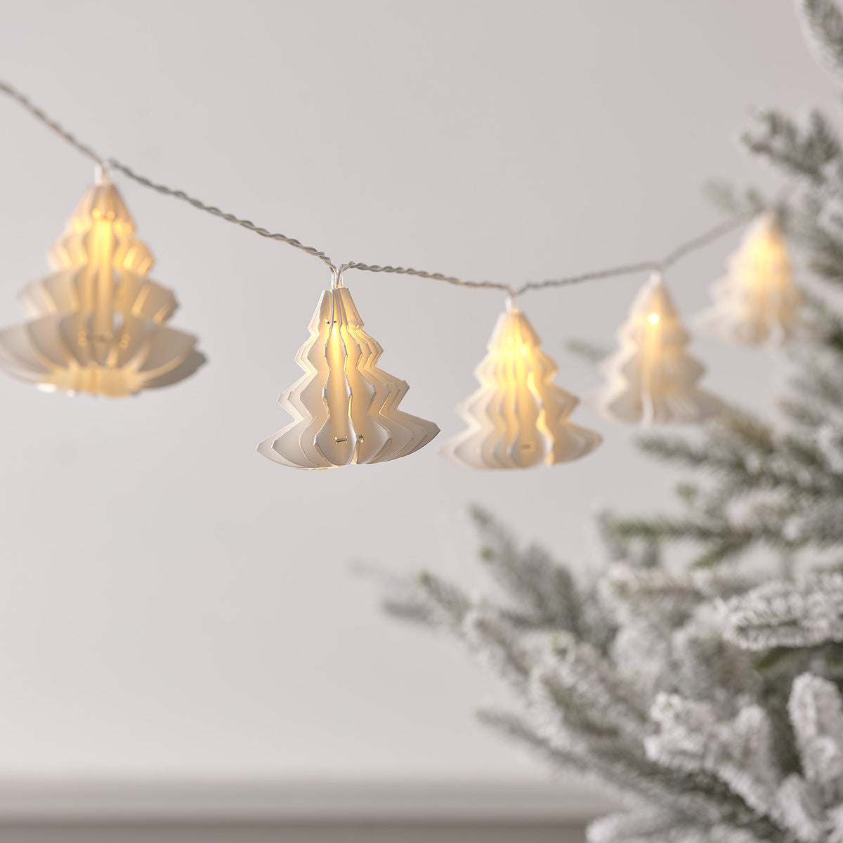 10er LED Lichterkette mit weißen Papierbäumen und warmweißem Licht vor hellem Hintergrund