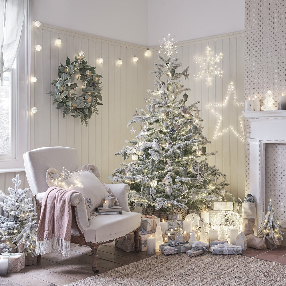 Weihnachtszimmer mit geschmücktem Baum und beleuchteter LED Schneeflocke als Baumspitze