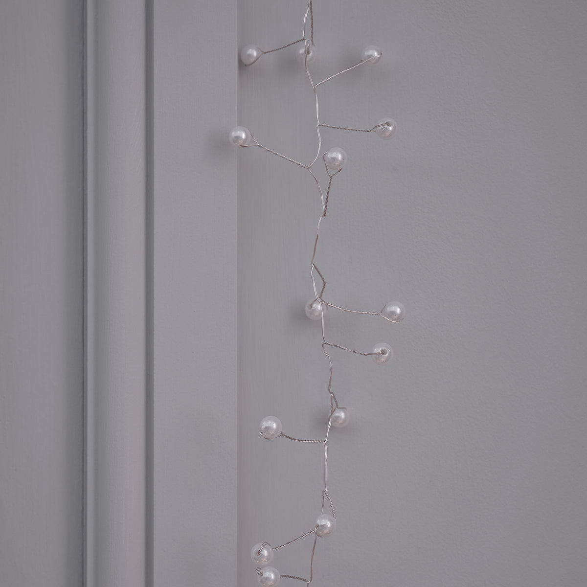 Perlencluster Lichterkette mit weißen Kugeln an grauer Wand ohne Licht