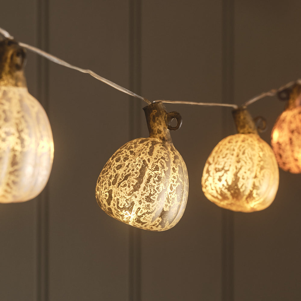 Nahaufnahme von zwei warmweiß leuchtenden Glas-Kürbissen an LED Lichterkette
