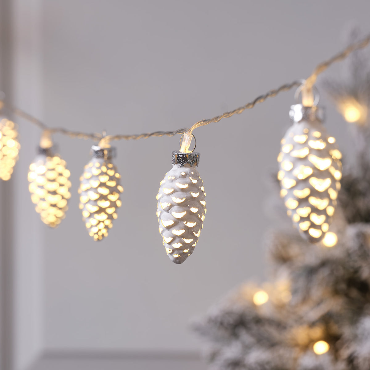 Nahaufnahme der beleuchteten LED-Glas-Tannenzapfen-Lichterkette mit silbernem Finish