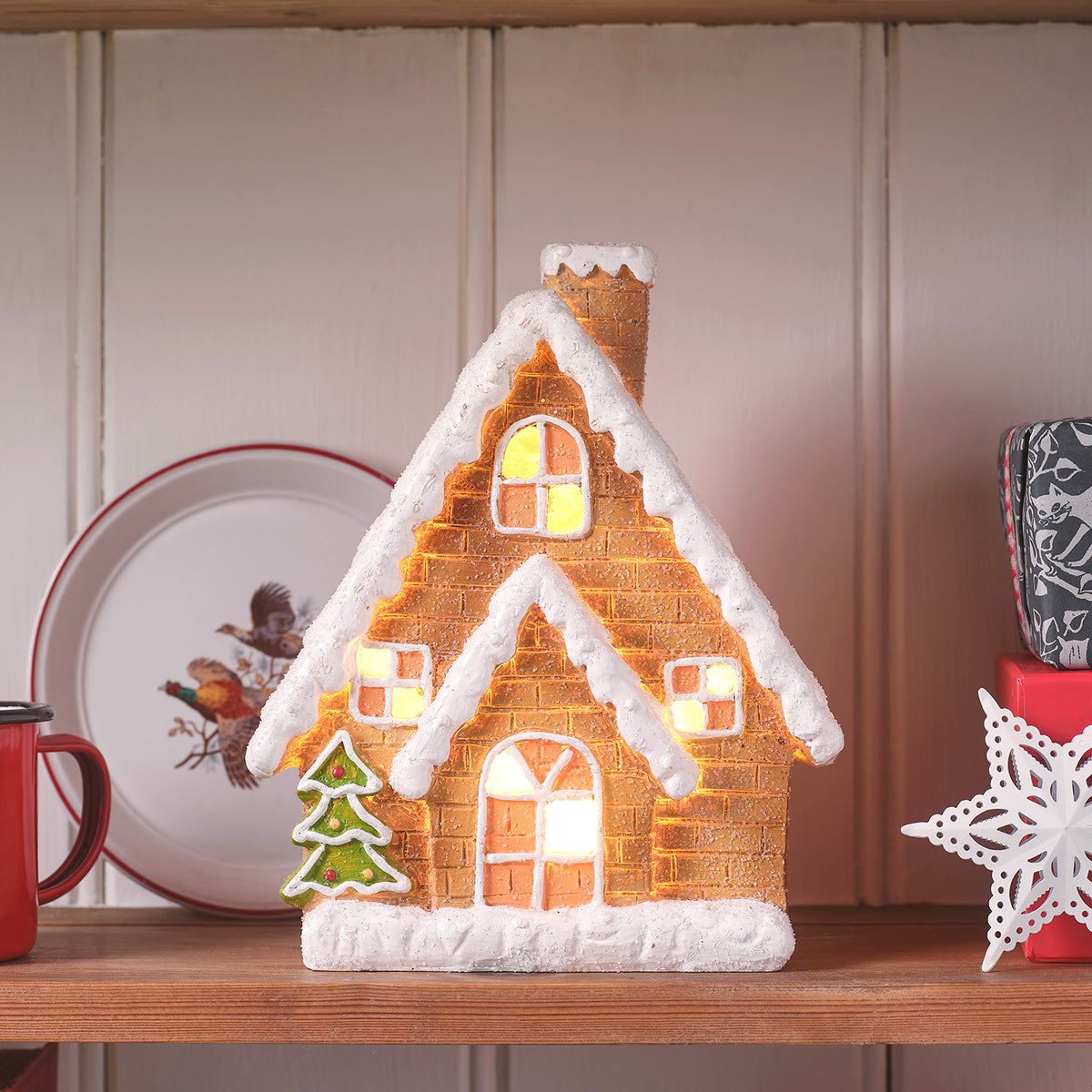 Vorderansicht des beleuchteten Keramik-Lebkuchenhauses mit Tannenbaum-Dekor