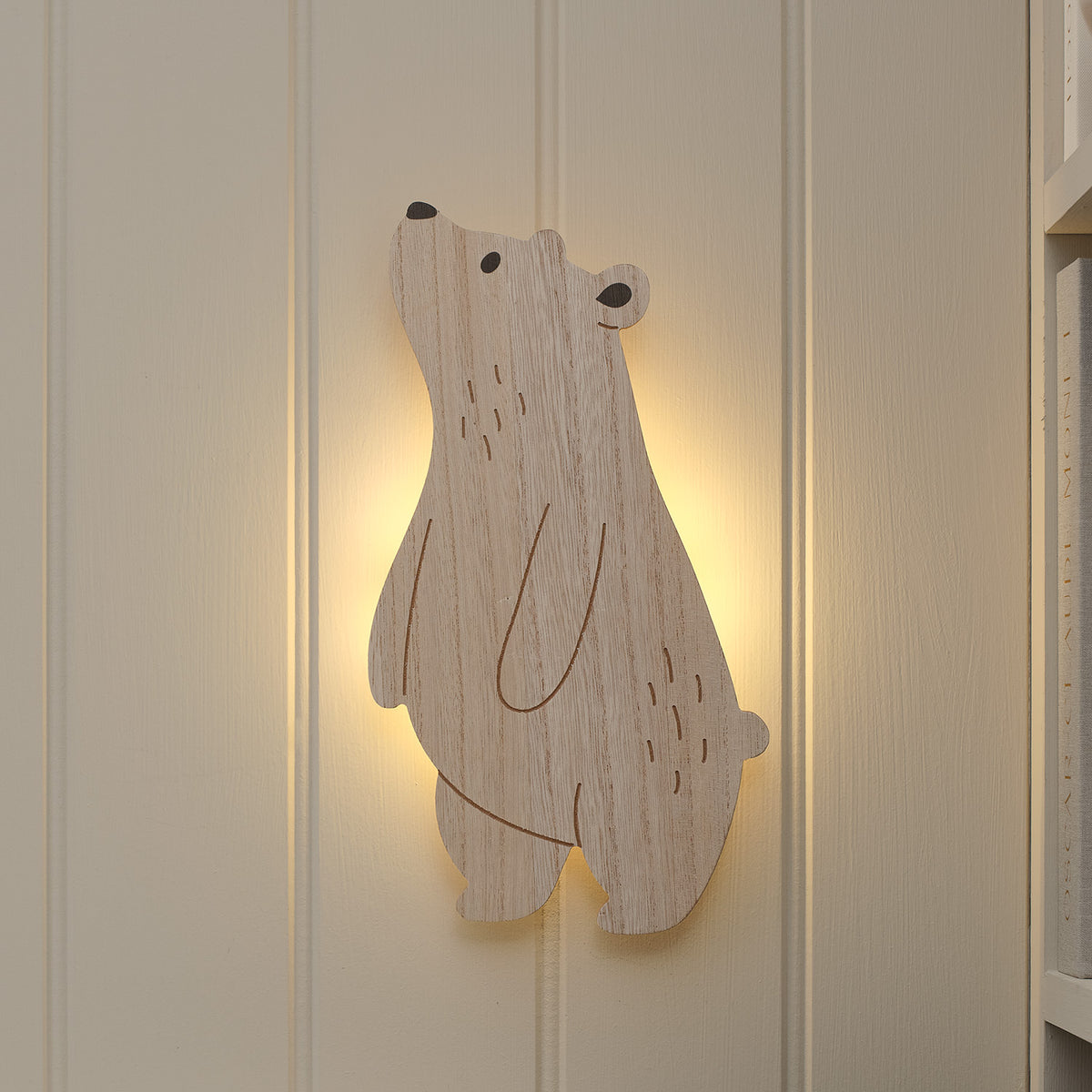 Holz-Wandlampe in Bärform leuchtet warmweiß an weißer Wand im Kinderzimmer