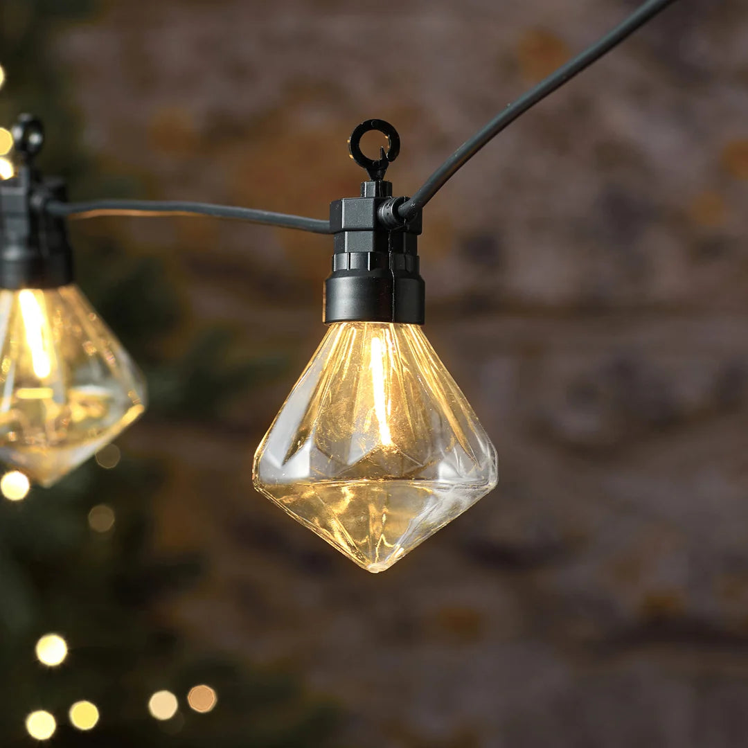 Detailansicht einer warmweißen diamantförmigen LED-Glühbirne an Lichterkette.