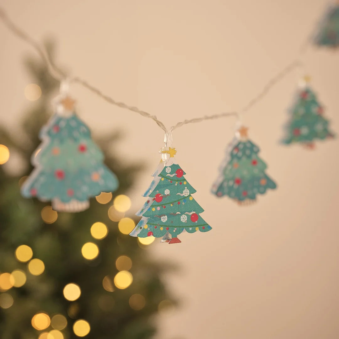 Lichterkette mit mehreren Tannenbaum-Anhängern vor Tannengrün.