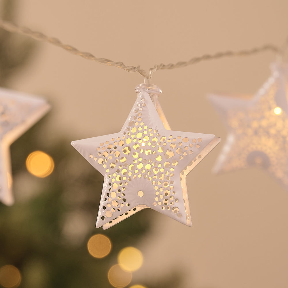 Nahaufnahme eines weißen Metallsterns mit filigranen Ausschnitten und warmweißem LED-Licht
