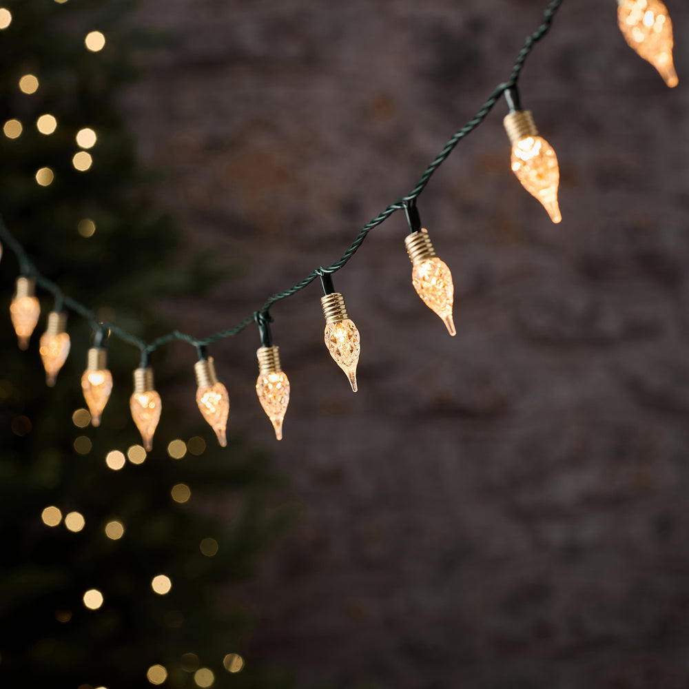 Warmweiße LED-Lichterkette mit 50 facettierten Tropfen an schwarzem Kabel vor dunklem Hintergrund