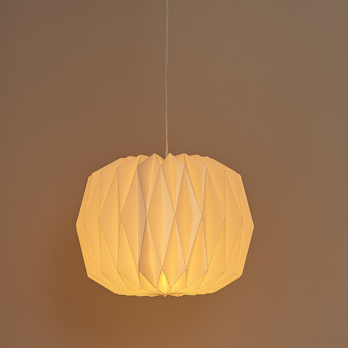 Weiße LED-Papierlaterne mit rautenförmiger Struktur leuchtet warmweiß an grauer Wand