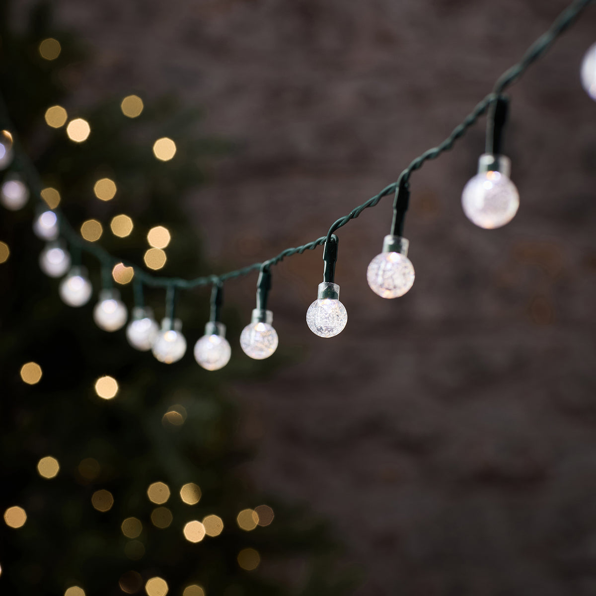 LED-Lichterkette Bubble Ball mit weißen Kugeln und grünem Kabel vor dunklem Hintergrund