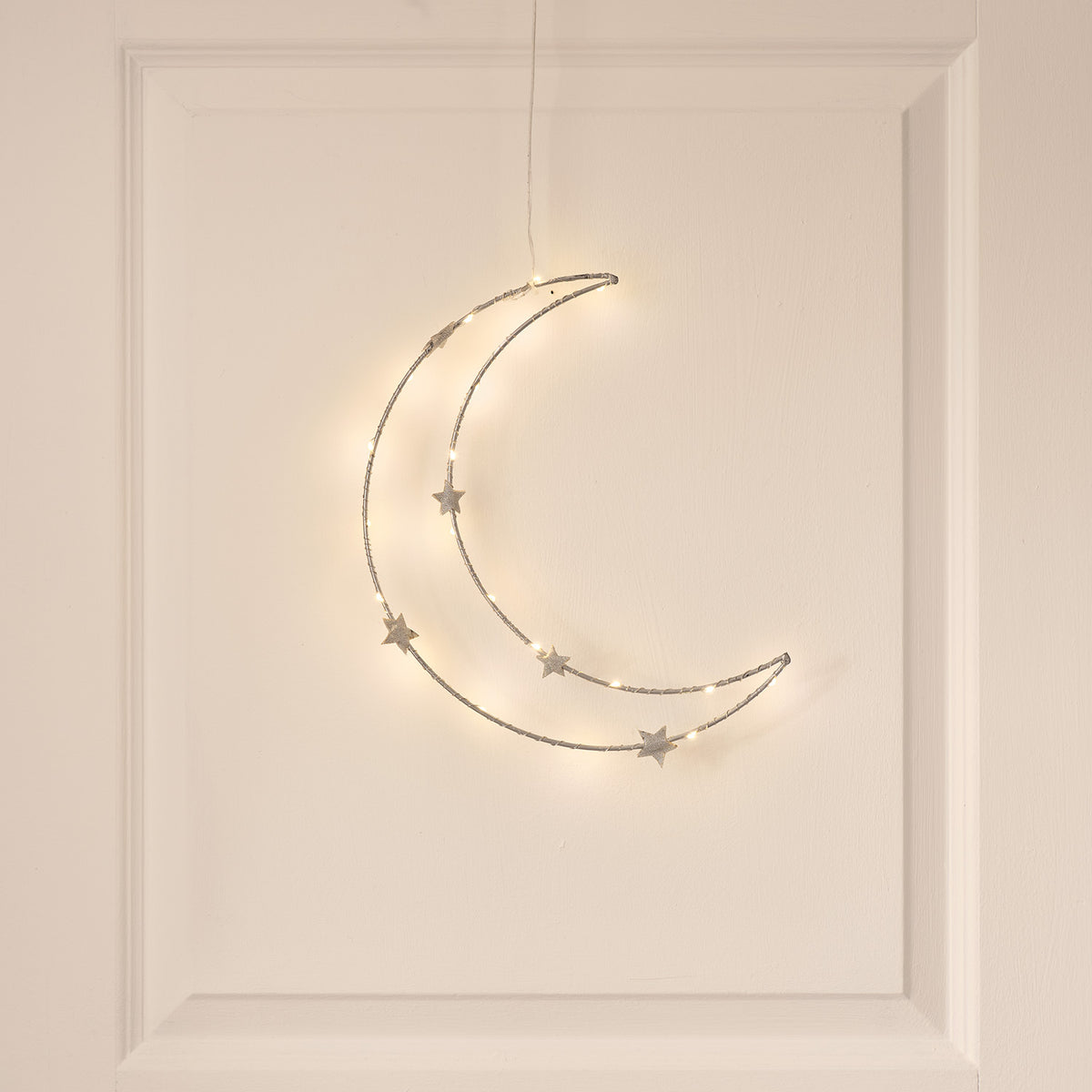 Warmweißer LED-Mond mit Sternen an weißer Wand hängend, leicht von unten fotografiert