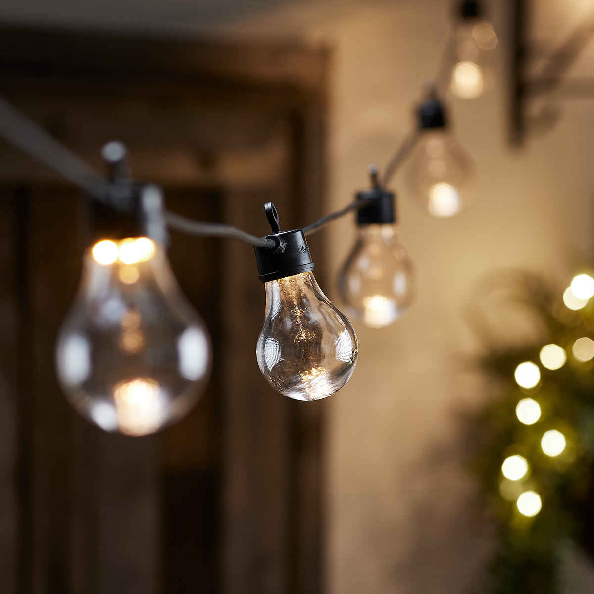 Detailaufnahme einer warmweißen Glühbirne der Lichterkette vor unscharfem Hintergrund