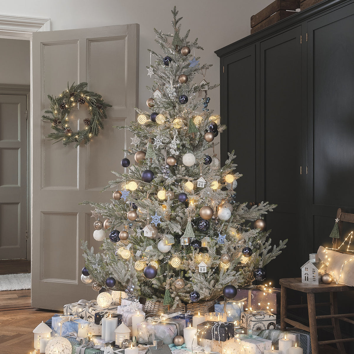 Weihnachtsbaum mit Kugeln und Lichterkette neben beleuchtetem LED-Weihnachtskranz an Tür