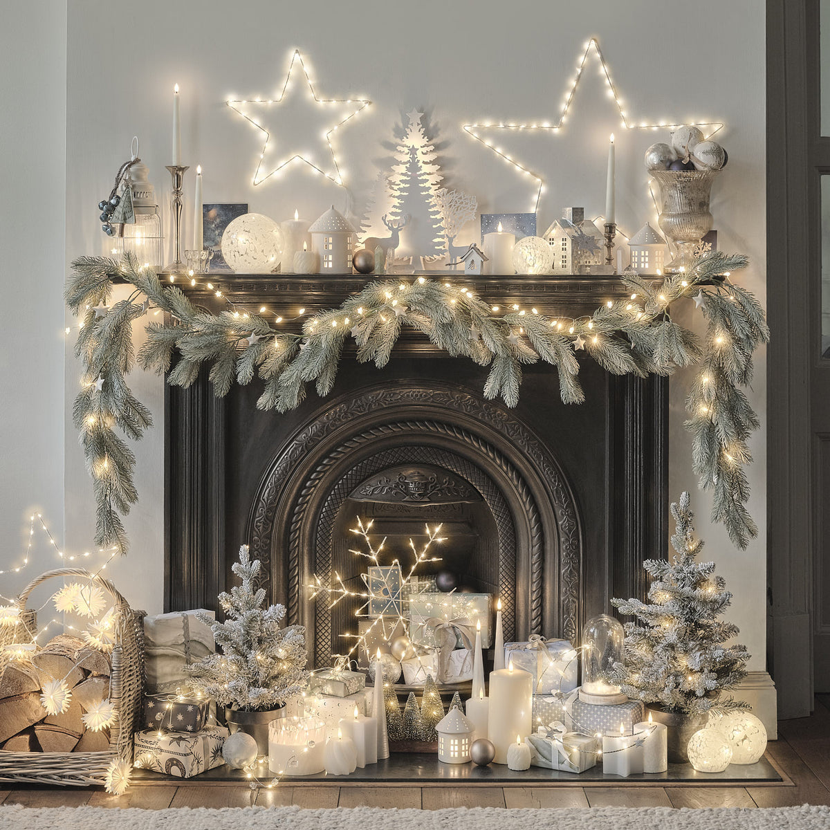 Weihnachtlich dekorierter Kamin mit LED-Tannengirlande, Sternenlichtern und zahlreichen Kerzen