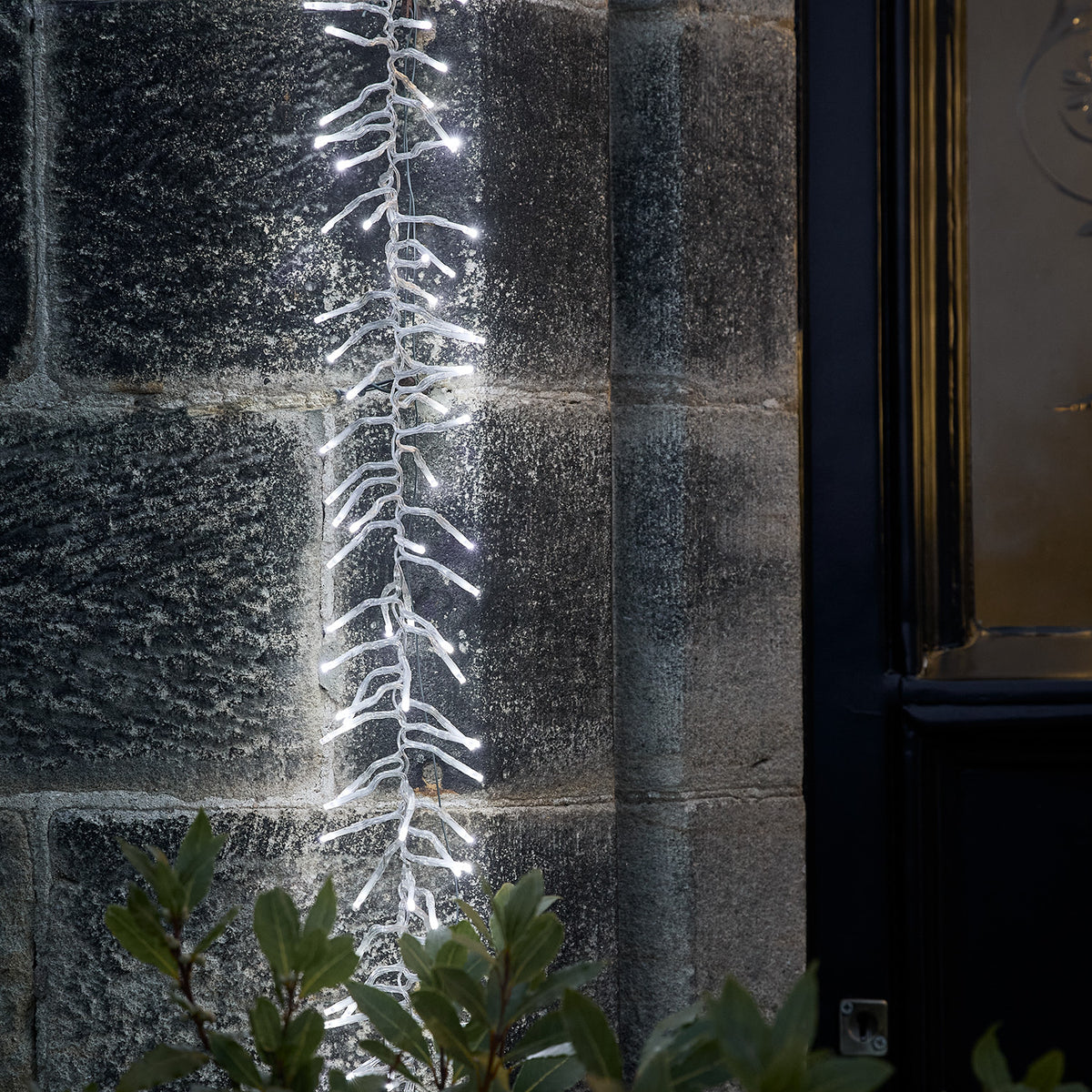 Weihnachtlich beleuchteter Hauseingang mit Lichterkranz an Tür und Lichterkette am Türbogen