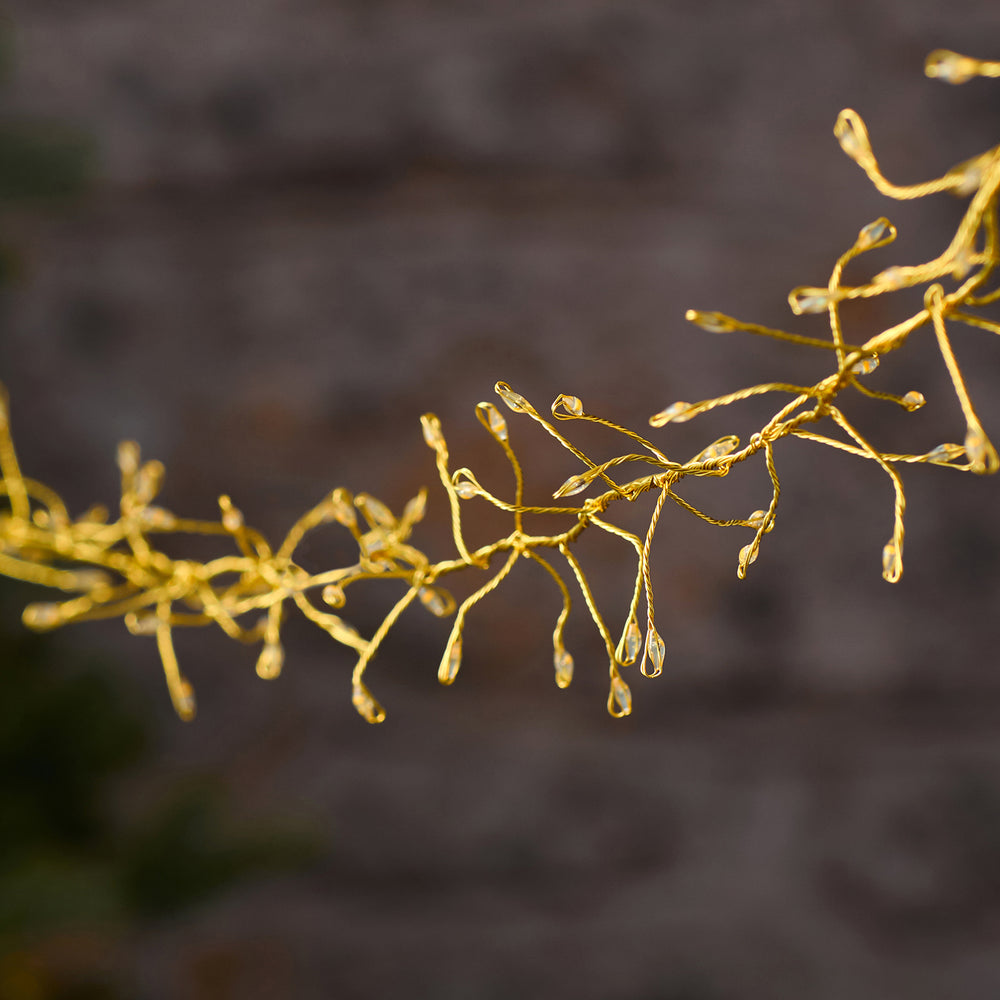 Nahaufnahme goldener Draht mit kleinen LED-Lichtpunkten der Cluster-Lichterkette