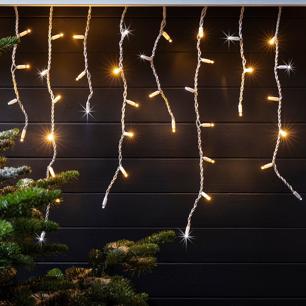 LED Eiszapfen-Lichterkette mit warmweißen und kaltweißen Lichtern an dunkler Holzfassade