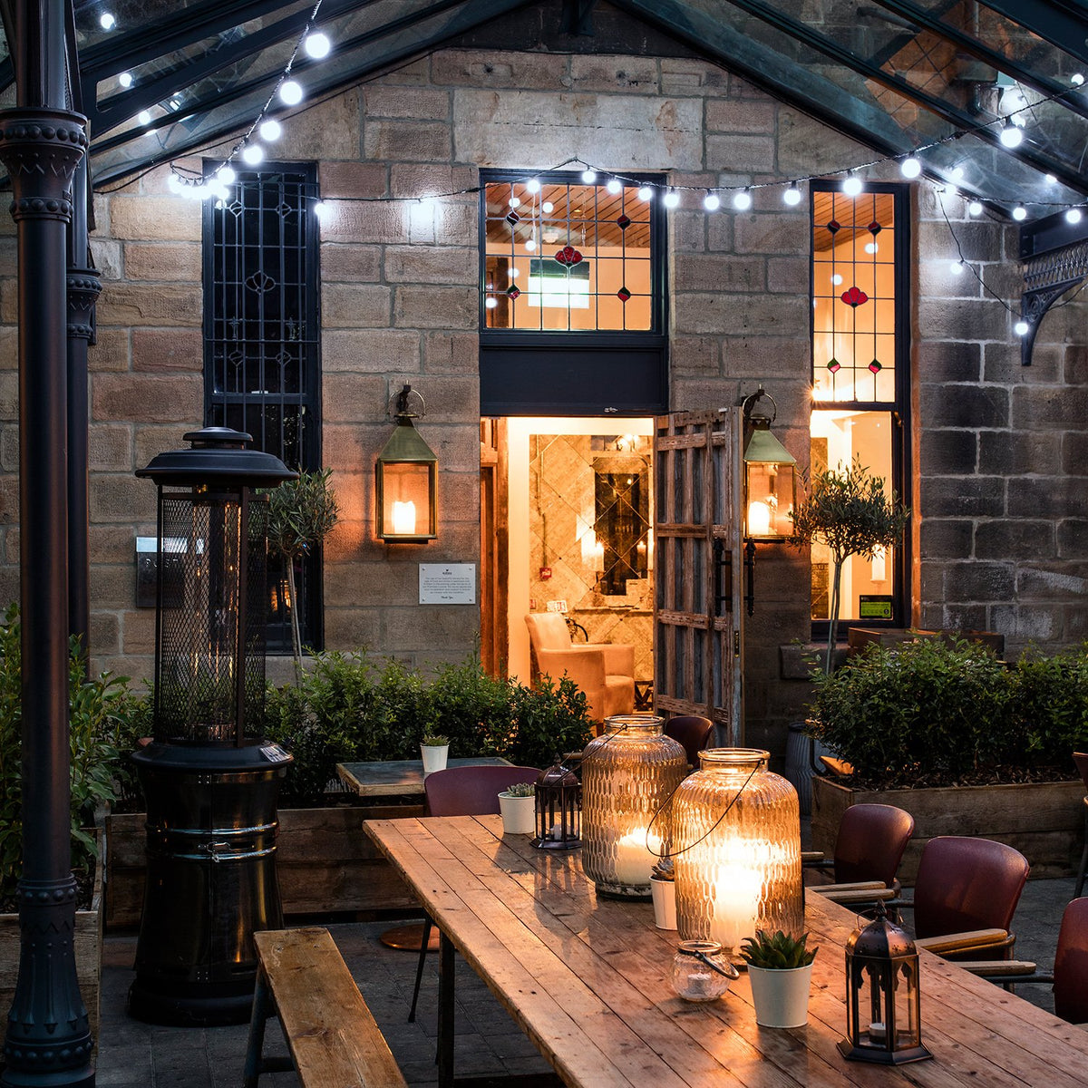 Pro Connect Lichterketten mit weißen Kugellichtern über einem Außenbereich mit Tischen und Kerzen