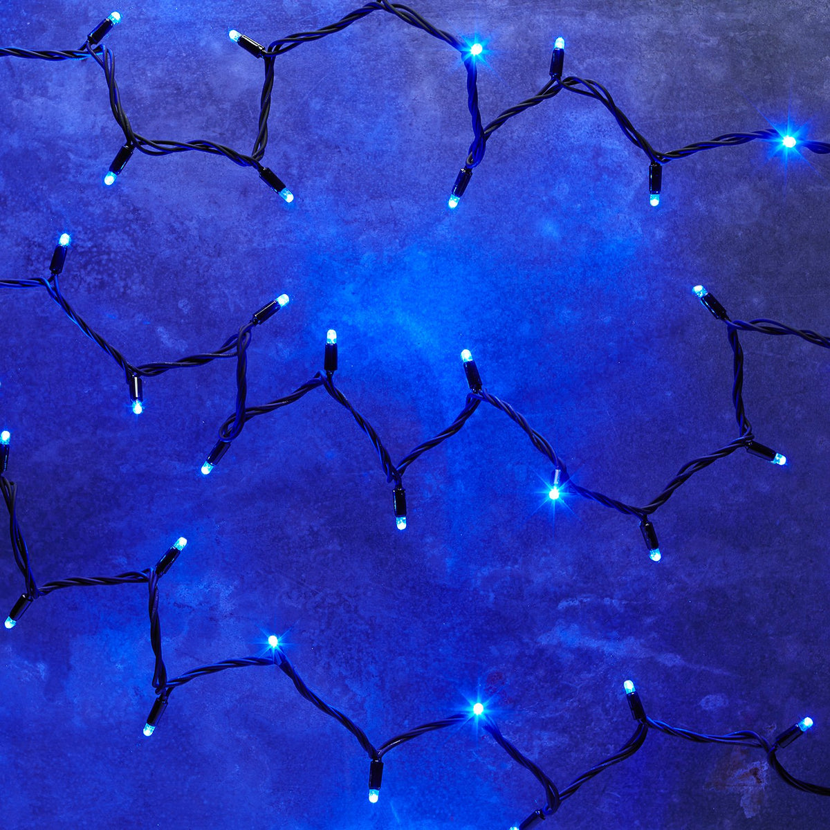 Detailaufnahme einer schwarzen Kabel-Lichterkette mit kleinen blauen LEDs auf grauem Untergrund
