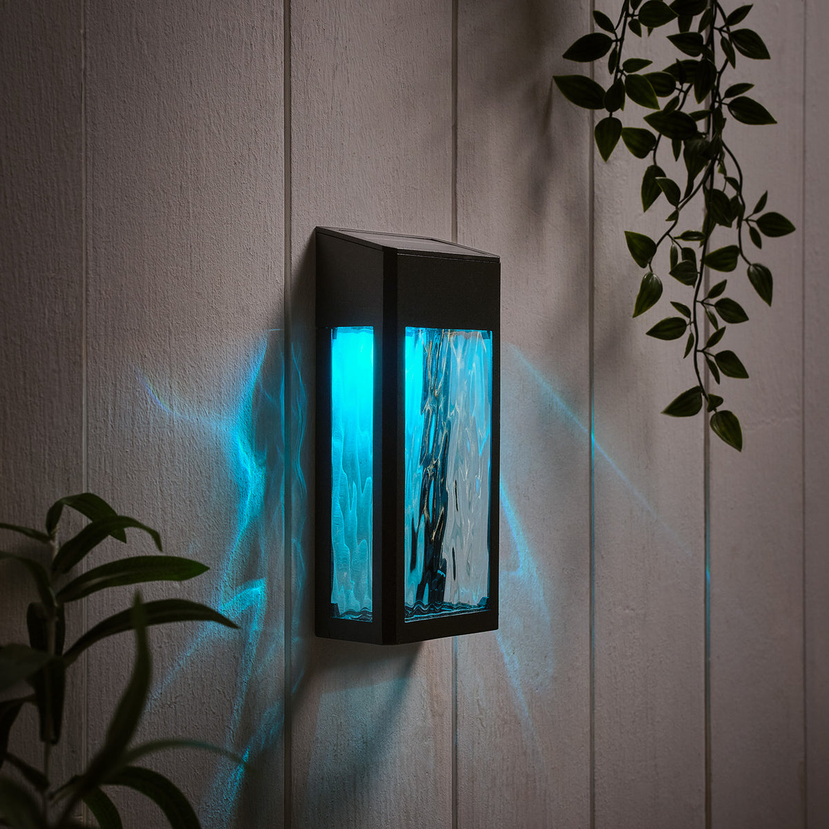 Solar-Wandleuchte mit hellblauem Licht und strukturierter Glasfront an weißer Wand