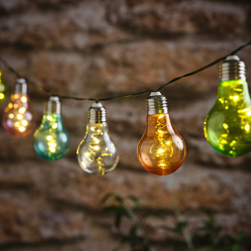 Solar-Lichterkette mit 10 bunten Glühbirnen in Pastellfarben vor unscharfem Hintergrund