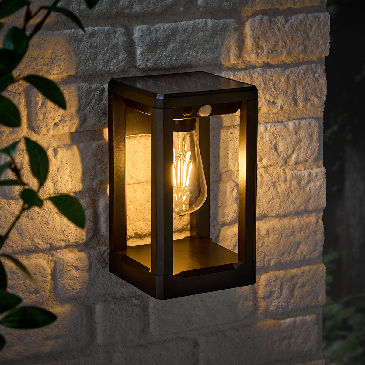 Solar-Wandleuchte Ashford mit warmweißem Licht an heller Steinwand montiert bei Nacht