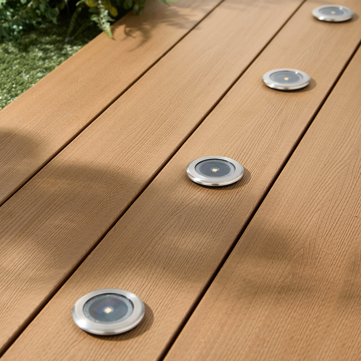 Vier silberne Solar-Spots ohne Licht in hellen Terrassendielen aus Holz