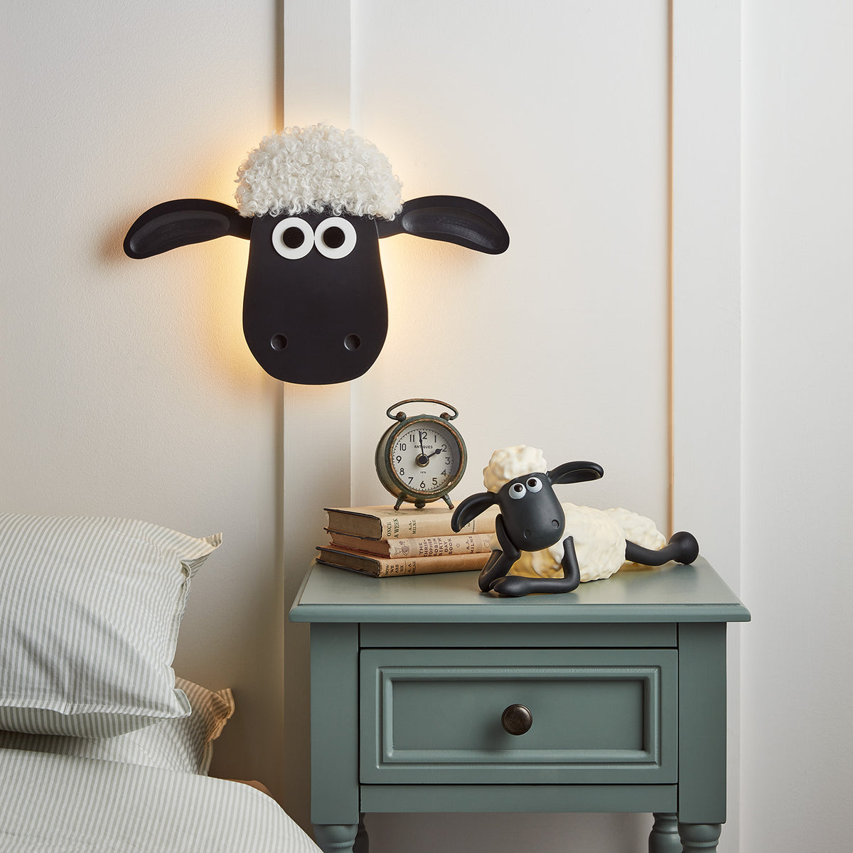 Shaun the Sheep Wandlampe über grünem Nachttisch mit Wecker und Shaun Figur