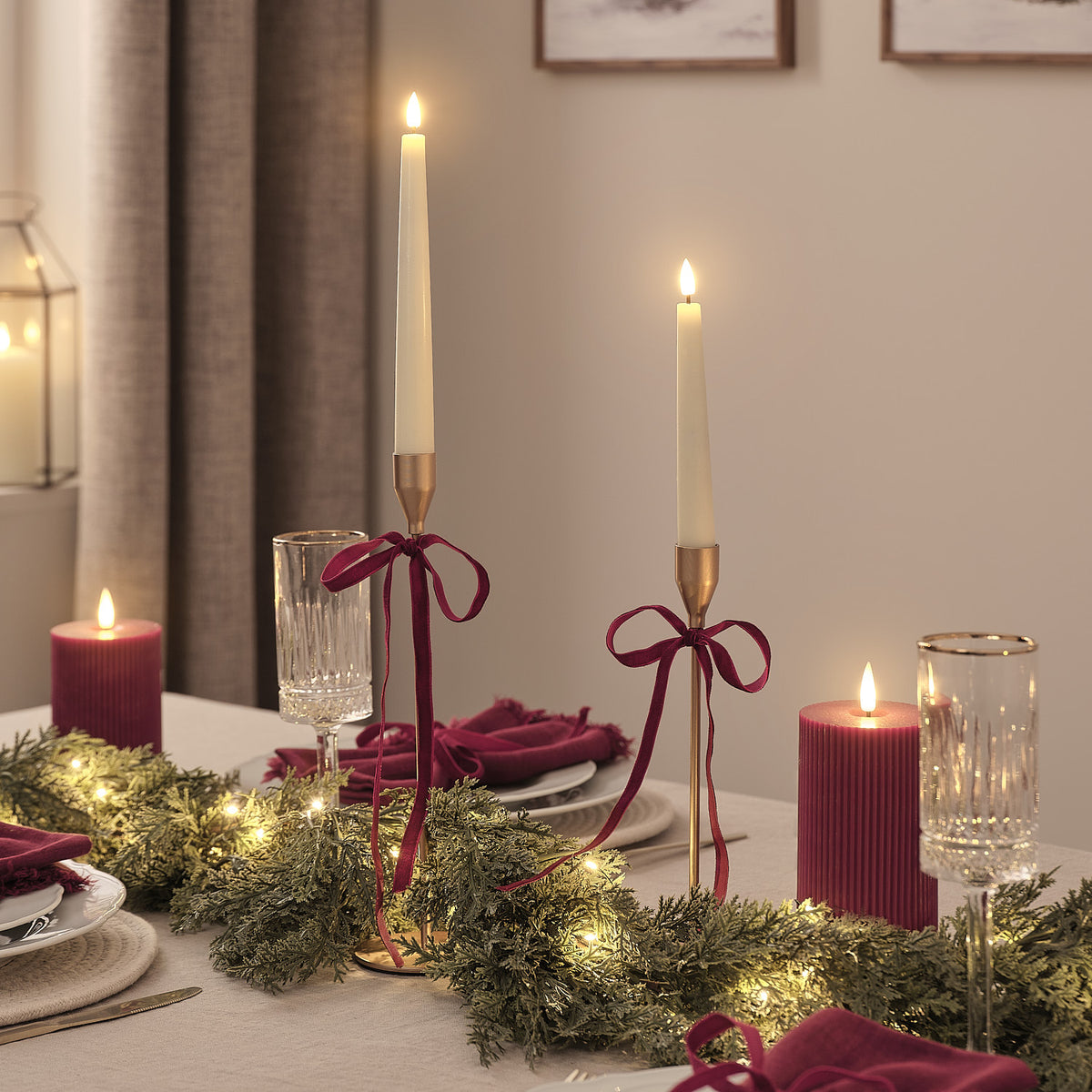 Festlich gedeckter Tisch mit Kerzen, roten Servietten und beleuchteter Weihnachtsgirlande