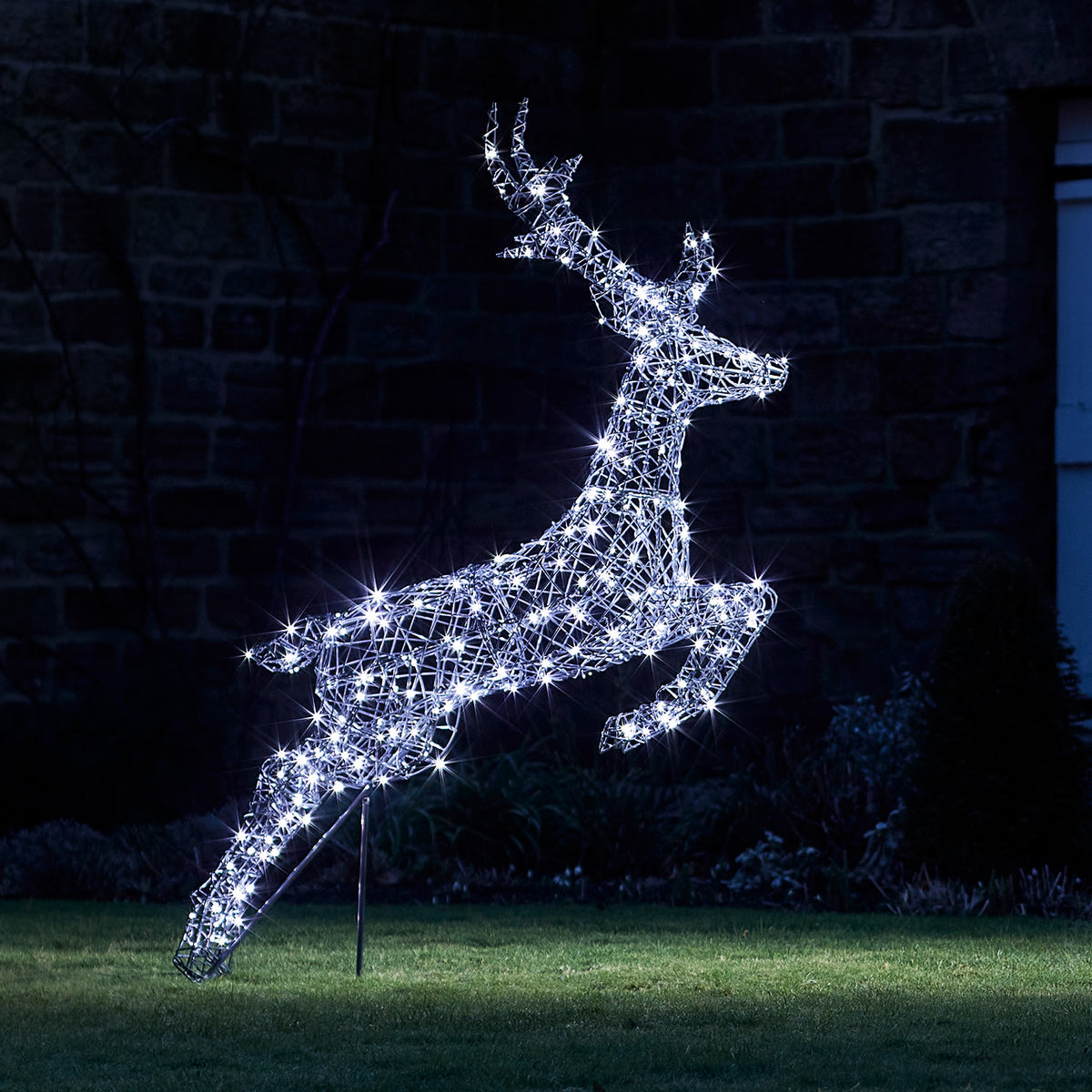 Springendes Rentier mit kühlen weißen LED-Lichtern beleuchtet vor dunklem Hintergrund