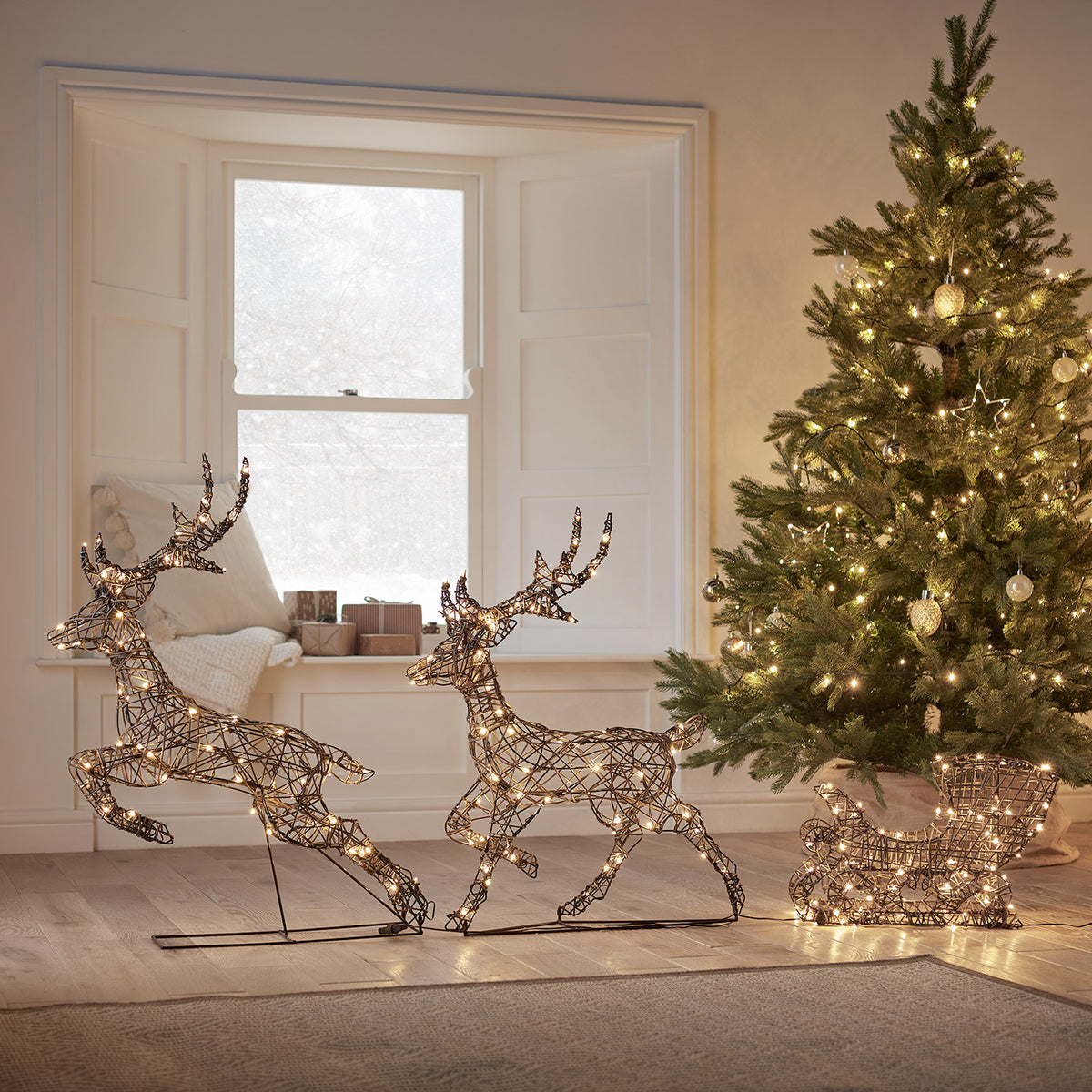 Solar-LED-Rentiere mit Schlitten neben geschmücktem Weihnachtsbaum in hellem Wohnzimmer