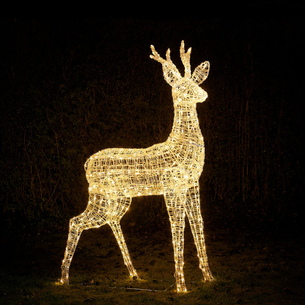 Großes Rentier aus Acrylgestell mit warmweiß leuchtenden LEDs im Garten bei Nacht