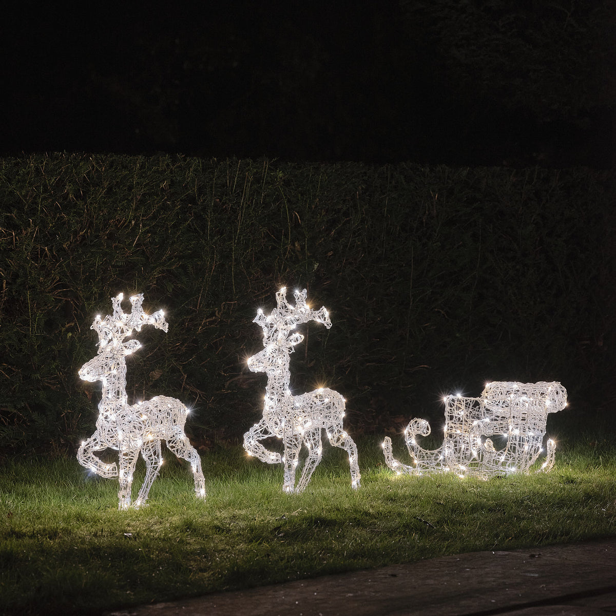 Solar-LED-Rentiere mit Schlitten in gemischtem Weiß- und Warmweißlicht auf Rasen bei Nacht