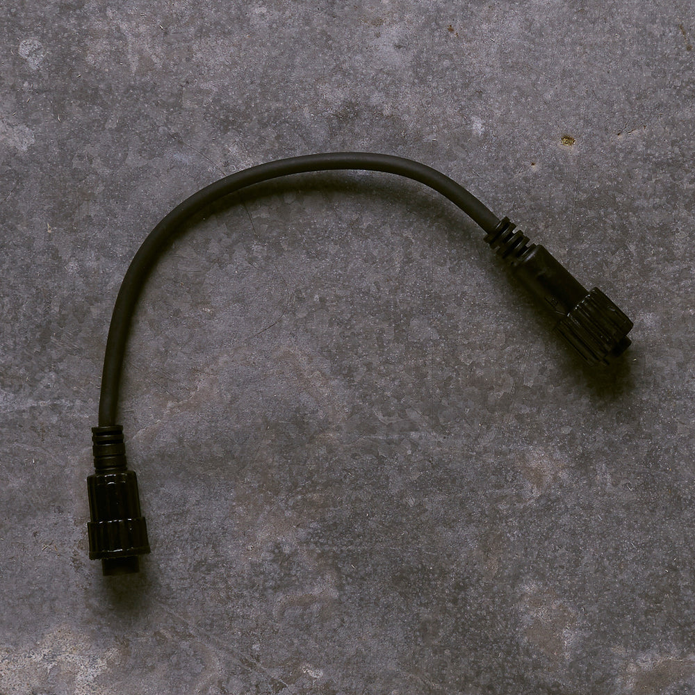 Schwarzes Pro Connect IP67-zu-IP44-Konverterkabel mit zwei Steckverbindern auf grauem Untergrund