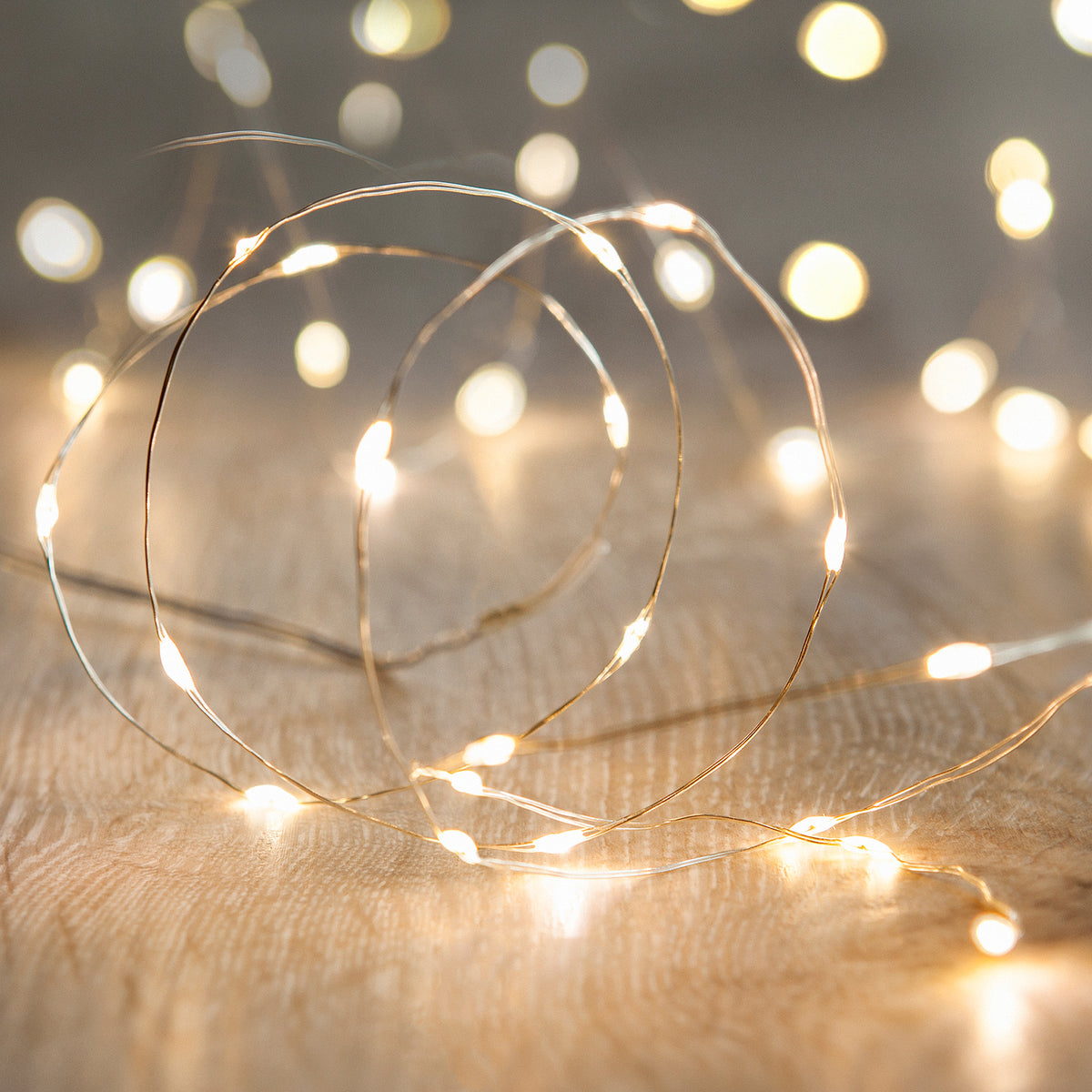 Nahaufnahme der warmweißen Micro USB Lichterkette auf hellem Holz mit unscharfem Hintergrund