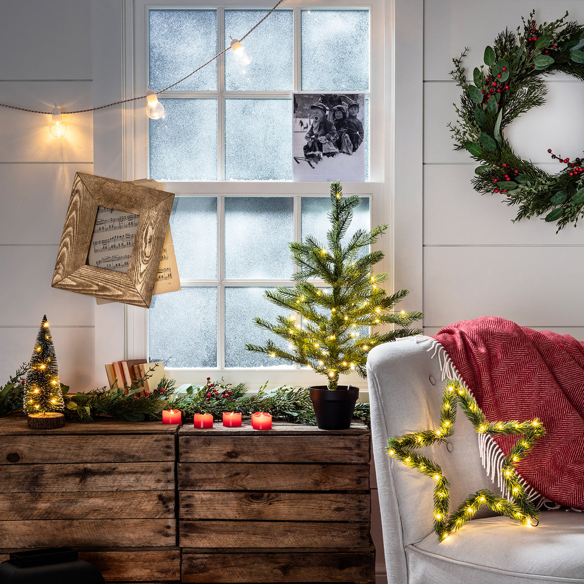 Weihnachtliche Fensterbank mit beleuchteten Tannen, roten LED Votivkerzen und Stern-Deko