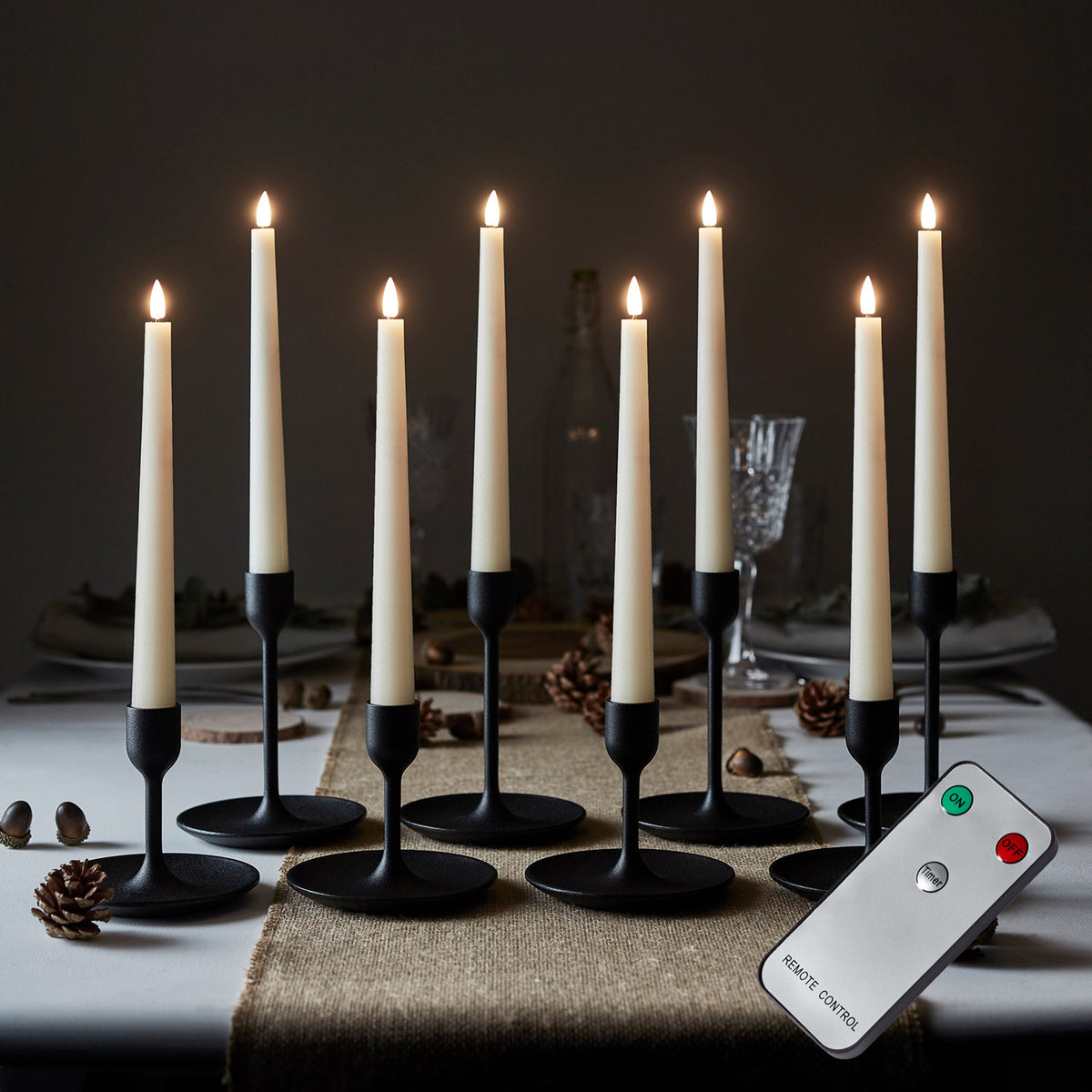 LED Stabkerzen in schwarzen Haltern mit Fernbedienung auf einem Tisch mit herbstlicher Dekoration