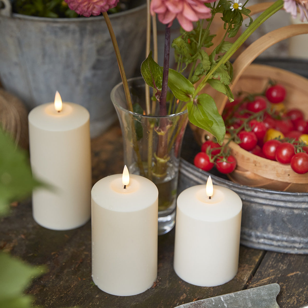 Drei TruGlow LED Kerzen mit warmem Licht auf Holztisch mit herbstlicher Dekoration