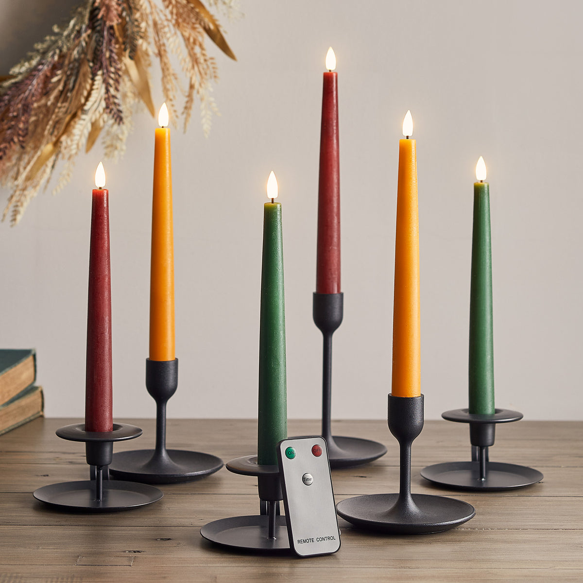 Sechs brennende LED Stabkerzen in Herbstfarben mit Fernbedienung auf Holztisch