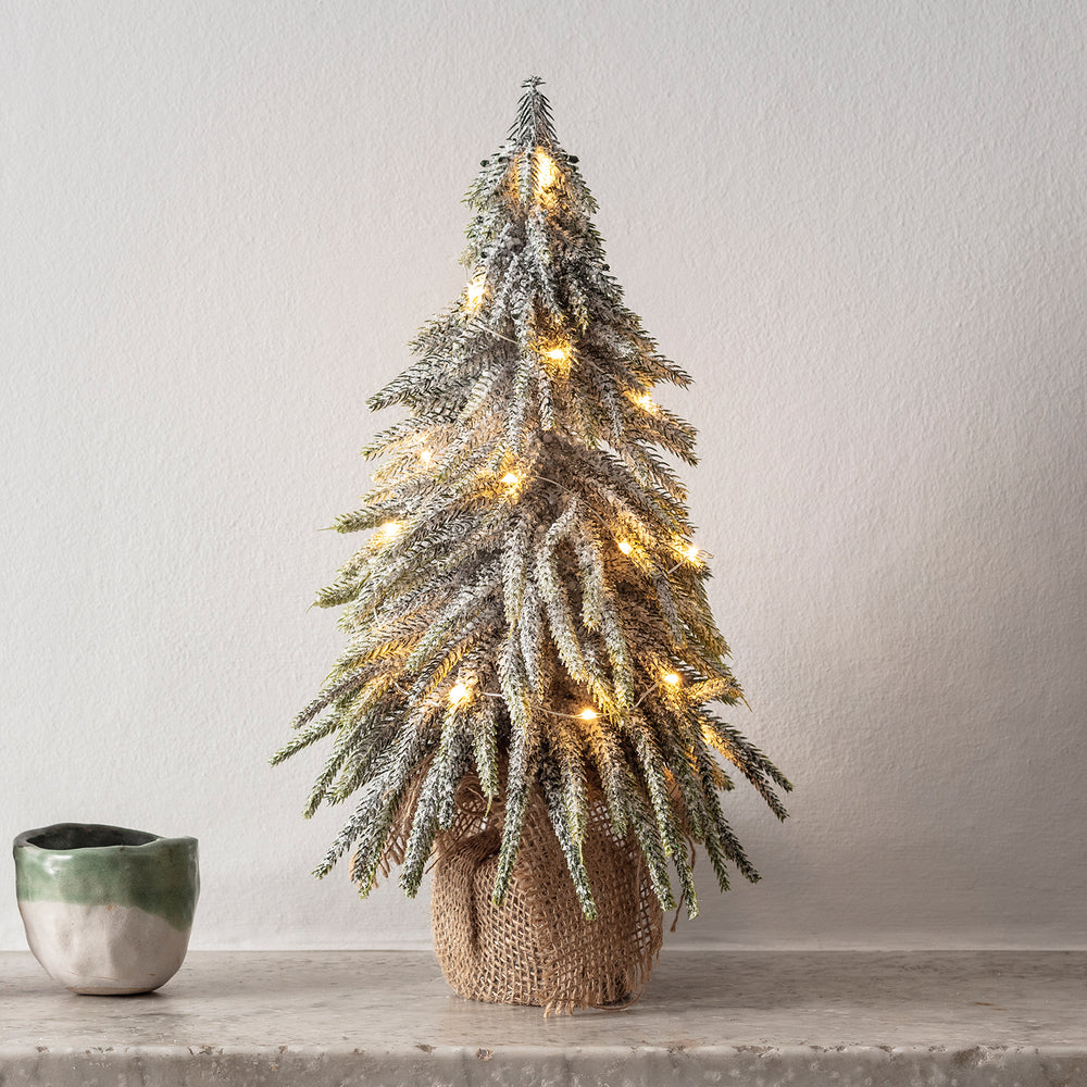 Nahaufnahme eines 35cm Mini Weihnachtsbaums mit Schnee und warmweißer Micro Lichterkette auf Marmorfläche