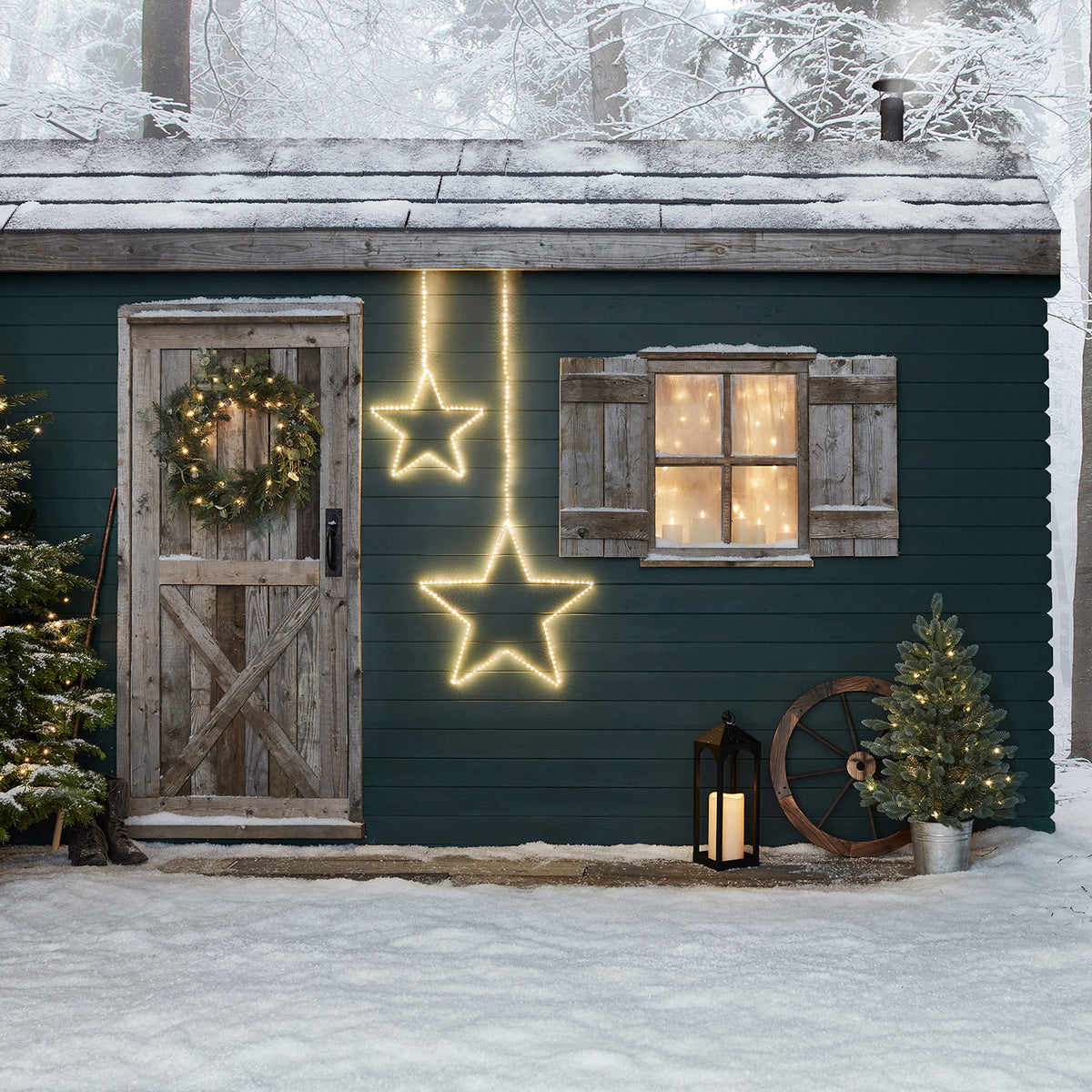 Zwei leuchtende LED-Sterne an der Außenwand eines Hauses im Schnee