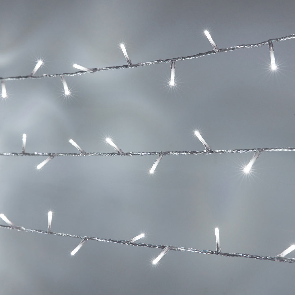 Weiße LED-Lichterkette mit transparentem Kabel und leuchtenden kleinen Lämpchen vor grauem Hintergrund
