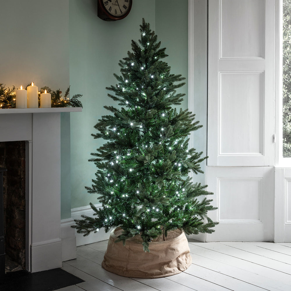 Weihnachtsbaum mit weißer LED-Lichterkette beleuchtet in modernem Wohnzimmer