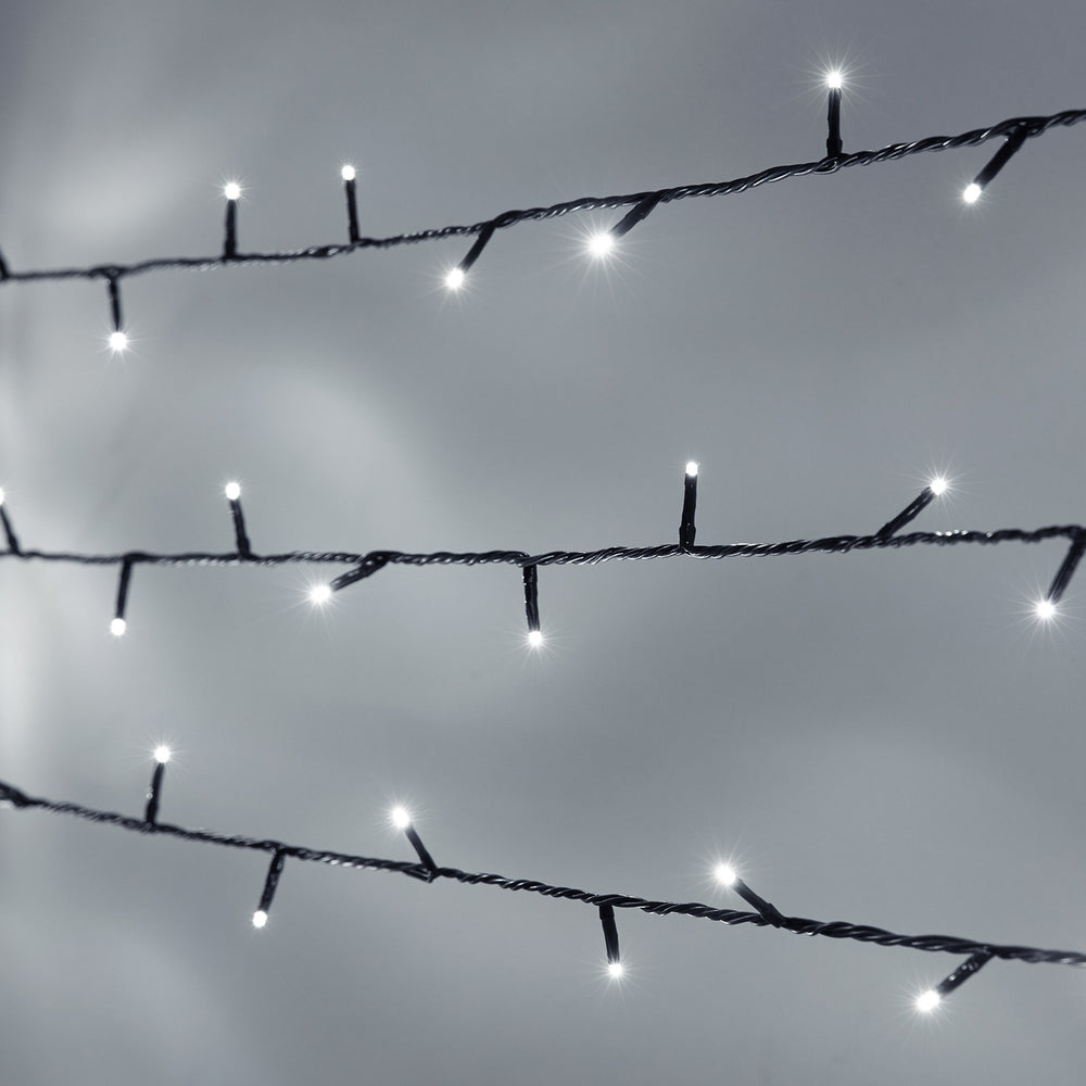 Nahaufnahme weiße LED Lichterkette mit grünem Kabel vor grauem Hintergrund