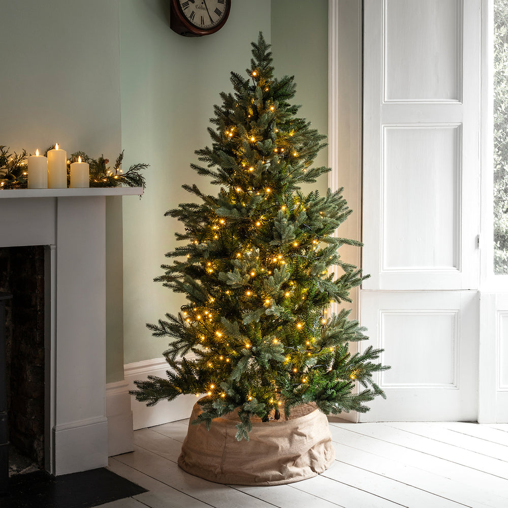 Weihnachtsbaum mit warmweißer LED-Lichterkette und Kerzen auf Kaminsims