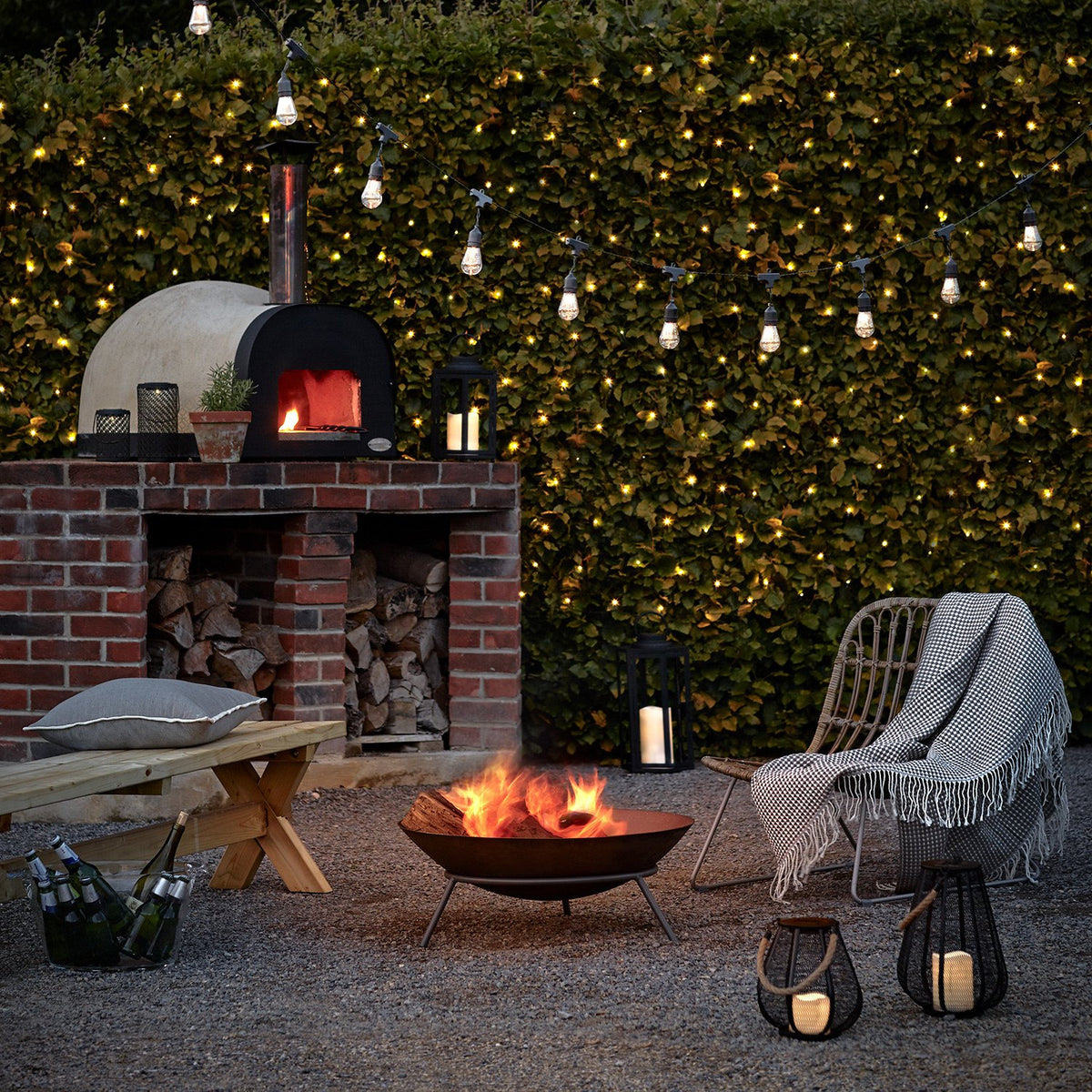Beleuchtete Hecke mit warmweißen LED Lichternetzen und Feuerstelle im Garten