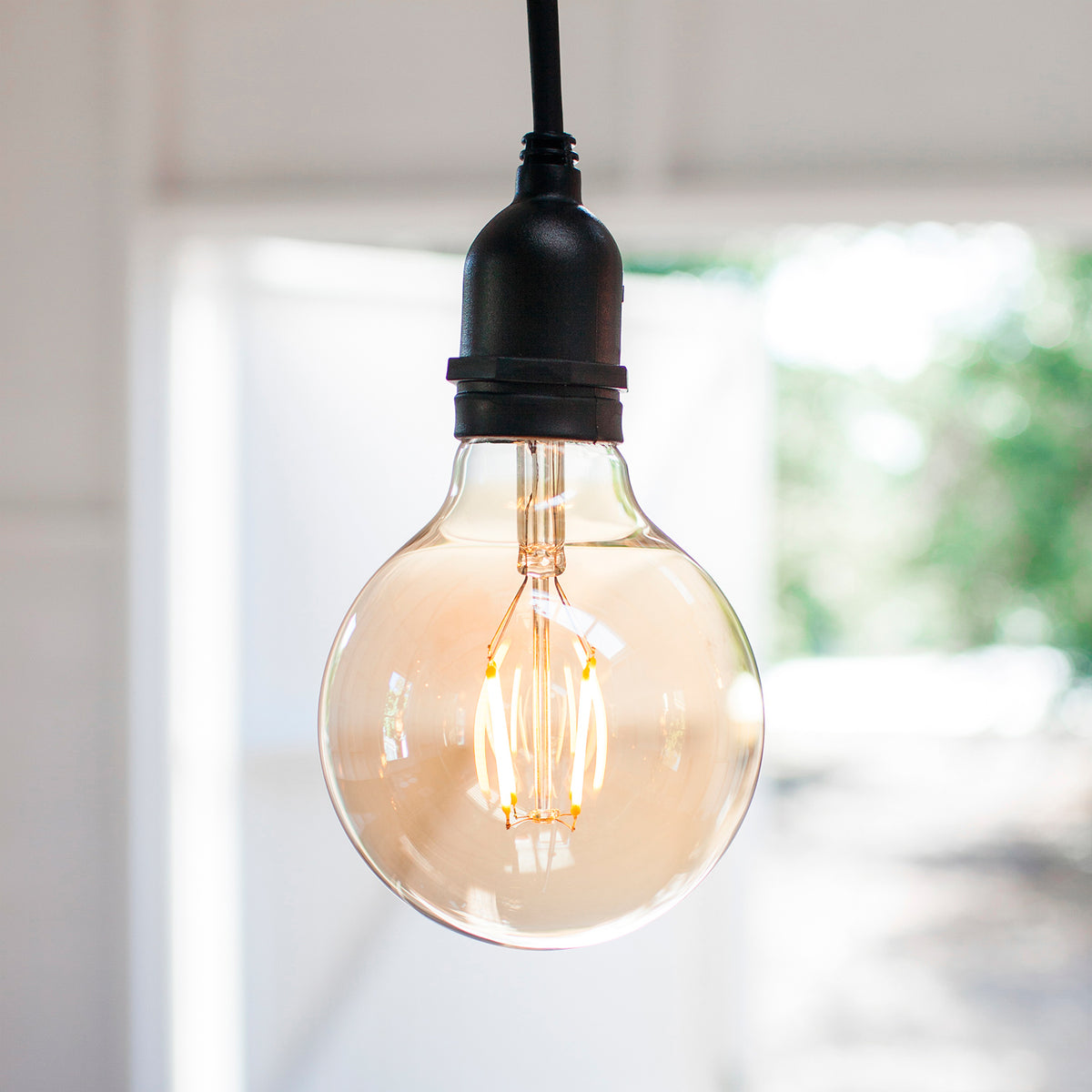 Große Globe LED Vintage Glühbirne mit bernsteinfarbenem Glas und schwarzer Fassung im Innenraum