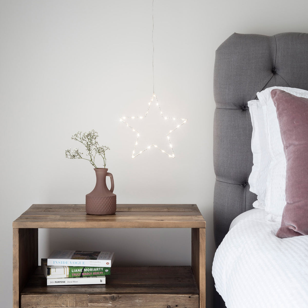 LED Stern mit warmem Licht auf Holztisch vor weißer Wand