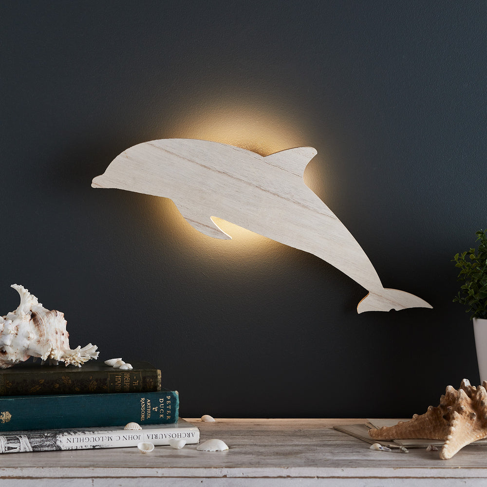 Delfin Wandlampe aus Holz mit warmweißem LED-Licht an dunkler Wand